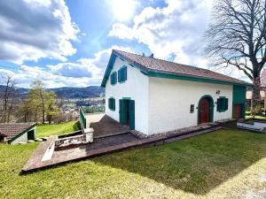 a small white house with a green door on a field at La Fermette du Patural in Ramonchamp