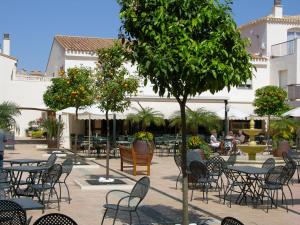 un patio al aire libre con mesas, sillas y un árbol en Buena Vista 7708 - Resort Choice, en La Manga del Mar Menor