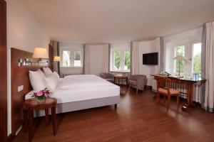 a bedroom with a large white bed and a desk at Hotel Schloss Eckberg in Dresden +53 photos