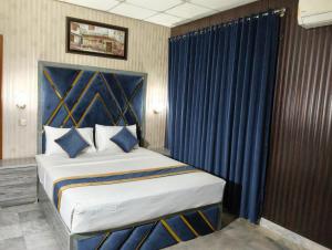 a bedroom with a large bed with blue curtains at Star Hotel Lahore in Lahore