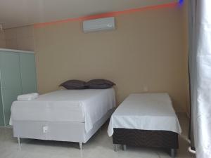 two beds in a room with white walls at Cantinho do sol in Maceió +14 photos