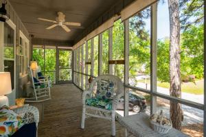 a screened porch with chairs and a ceiling fan at Beaching & Griping by Oak Island Accommodations in Oak Island