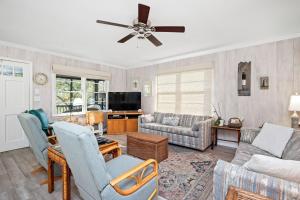 a living room with a couch and a ceiling fan at Beaching & Griping by Oak Island Accommodations in Oak Island