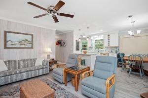a living room with a couch and chairs and a kitchen at Beaching & Griping by Oak Island Accommodations in Oak Island
