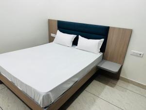 a bed with white sheets and a blue headboard at Hotel Loya Bti in Bathinda