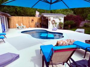 a swimming pool with chairs and an umbrella at Romantic Beach Style Cottage close to everything! in Whitehouse Plantation +22 photos