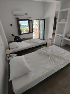 three beds in a room with a window at John's Guesthouse in Ksamil