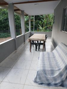 a patio with a table and a bench on a porch at Kitnet na mata atlantica in Ubatuba