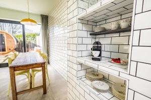 a kitchen with white tile walls and a table at Ferox Stay in Varsenare +25 photos