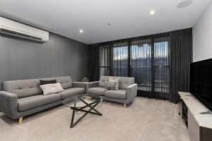a living room with a couch and a tv at The Piastri at Midnight in Braddon