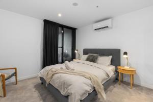 a white bedroom with a large bed and a window at The Piastri at Midnight in Braddon