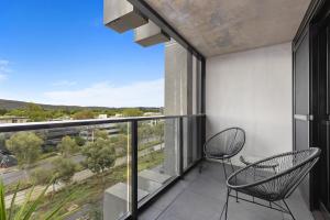 a balcony with two chairs and a view of a city at The Piastri at Midnight in Braddon