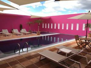 une piscine avec des chaises et des tables à côté d'un mur rose dans l'établissement Hotel Boutique Casareyna, à Puebla