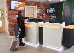a woman with a suitcase standing at a welcome counter at easyHotel Croydon in Croydon