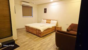 a small room with a bed and a chair at Hotel ShivInn in Gandhinagar