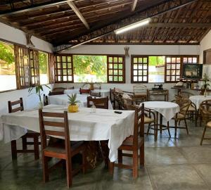 a restaurant with white tables and chairs and windows at Pousada PauBrasil in Barra Grande