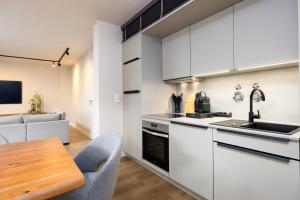a kitchen with white cabinets and a wooden table at Stylische Penthouse - Maisonette - Wohnung im edlem Design mit Balkon, Dachterrasse und kostenloser Tiefgarage im Herzen von Markkleeberg - Neuseenland in Markkleeberg