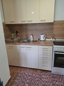 a kitchen with white cabinets and a sink at Horizont Cemerno in Podborina
