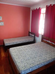 two beds in a room with red walls at Casa de temporada em Araruama in Araruama +13 photos