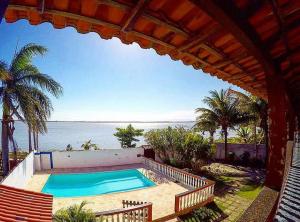 an outdoor swimming pool with a view of the ocean at Casa de temporada em Araruama in Araruama