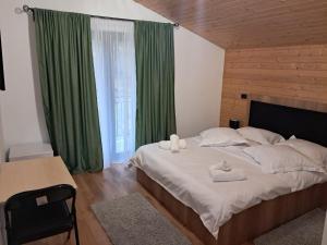 a bedroom with a large bed with green curtains at Casa dintre Brazi in Statjunea Borsa