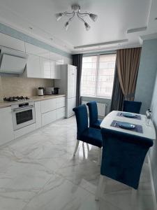 a kitchen with a table and blue chairs in a room at Golden Era Relax in Odesa