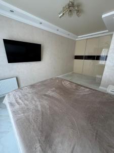 a bedroom with a large bed and a flat screen tv at Golden Era Relax in Odesa