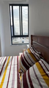 a bed with a striped comforter and a window at Kevin Island House in Ilhéu de Santa Maria