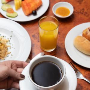 a table with plates of food and a cup of coffee at Hotel Habitel Select in Bogotá