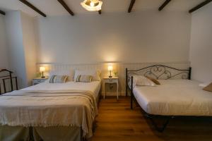two beds in a room with two tables and two lamps at Ca'Bastian-Guest House in Moruzzo