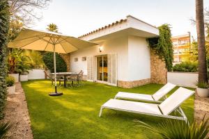 a lawn with a table and chairs and an umbrella at Nura Houses Condor in Playa de Palma