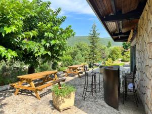 a patio with picnic tables and a trash can at L'Olivada, villa d'exception in Ganges