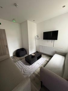 a living room with a couch and a tv on the wall at Large 6 Bed 6 Bathroom House - Ideal For Families, Large Groups, Contractors & Business Travellers in Watford