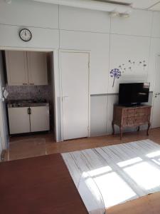 a living room with a tv and a clock on the wall at Willa Witsari 27m2 in Kokkola
