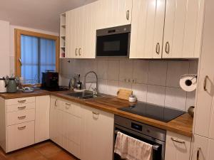 a kitchen with white cabinets and a sink and a microwave at Surya Villa Holistic Stay Prenzlauer Berg in Berlin
