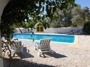 a swimming pool with two white chairs next to it at Quinta Martins in Loulé