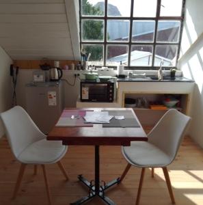 a kitchen with a wooden table and two white chairs at Cerro Chaltén House - Deptos in El Chalten