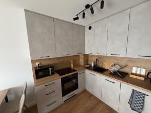 a kitchen with white cabinets and a sink and a microwave at Apart Apartamenty Łowiecka 4A Free Parking in Leszno +16 photos