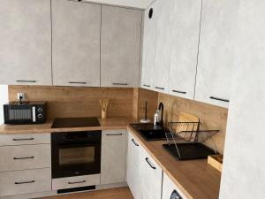 a kitchen with white cabinets and a black microwave at Apart Apartamenty Łowiecka 4A Free Parking in Leszno