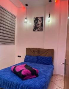 a bedroom with a bed with blue sheets and pink walls at saviohome in Ouarzazate