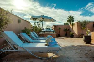 - un ensemble de chaises longues bleues et un parasol sur la terrasse dans l'établissement Riad Nasreen, à Marrakech