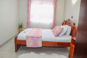 a bedroom with a bed with a wooden headboard and a window at D&H Homes Milimani Nakuru-Elegant 2 Bedroom Apartment in Nakuru +30 photos