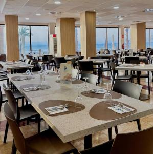 a dining room with tables and chairs and the ocean at Hotel & Spa Peñiscola Palace in Peniscola