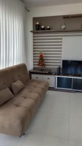 a living room with a couch and a christmas tree at Apartamento Completo Duas Quadras do Mar in Capão da Canoa