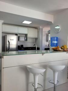 a kitchen with white cabinets and a counter with stools at Apartamento Completo Duas Quadras do Mar in Capão da Canoa