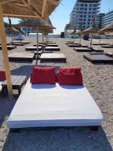 a bed with two red pillows on a beach at Premium Lakeside Apartament Building Stefan in Mamaia