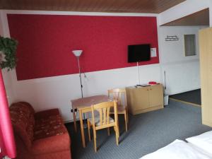 a room with a table and a couch and a tv at Hotel Am Stadtwall in Anklam