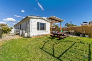 a tiny house with a picnic table in the yard at Ocean Spray in Lancelin