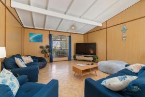 a living room with blue couches and a flat screen tv at Ocean Spray in Lancelin