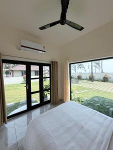 a bedroom with a white bed and a large window at LAGUNA BLU beach villa in Irimbranallūr